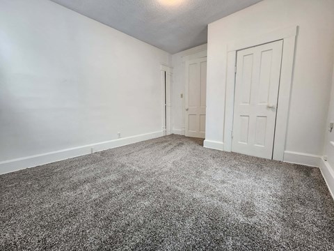 a bedroom with a carpeted floor and a white door