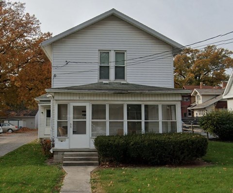 a white house with a porch in the grass