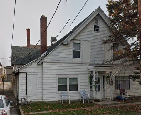 A white house with a grey roof and a small porch.