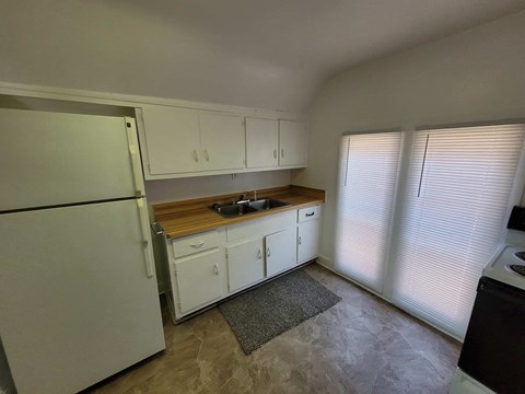 A kitchen with white cabinets and a refrigerator.