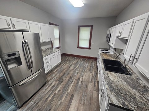 A kitchen with a stainless steel refrigerator and wooden flooring.