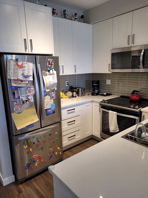 A kitchen with a fridge covered in magnets and a white counter top.
