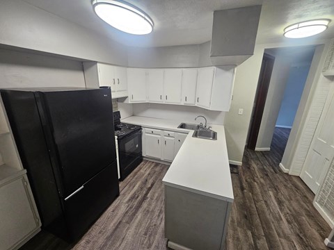 A kitchen with black appliances and white cabinets.