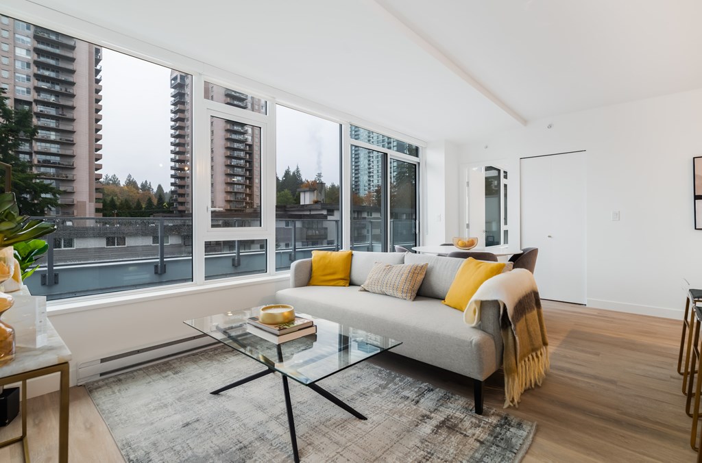 A modern living room with a grey couch and a glass coffee table.