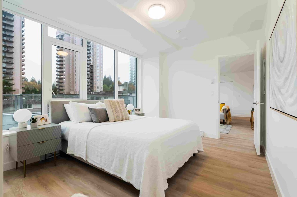 A bedroom with a large bed and a view of a city skyline.