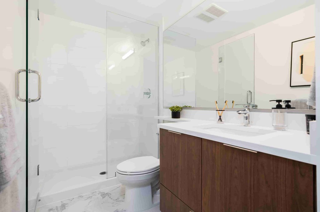 A white toilet sits in a bathroom with a marble floor and a white sink.
