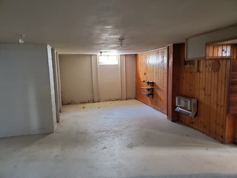 a living room with wood paneling on the wall and a concrete floor
