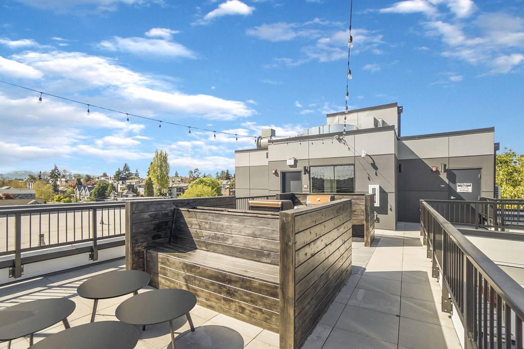 a rooftop patio with tables and chairs and a building in the background