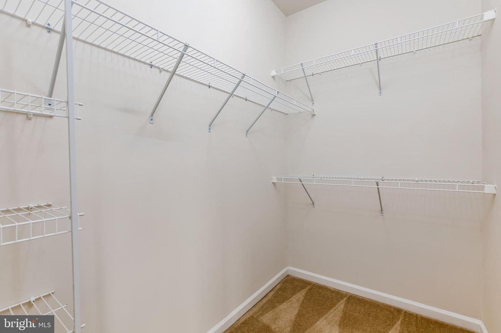 a spacious closet with shelves and a mirrored closet door