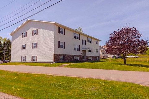 A two-story building with a red tree in front.