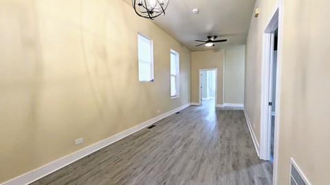 an empty living room with wood floors and a ceiling fan
