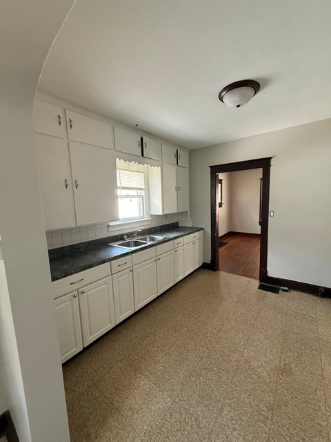 A kitchen with white cabinets and a brown floor.
