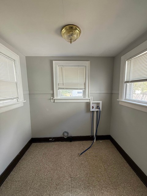 A room with a window, a sink, and a vacuum cleaner.