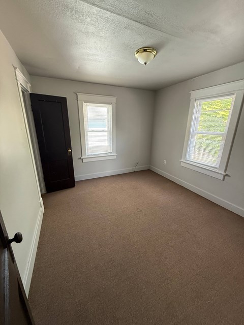 A room with a carpeted floor, a door, and a window.