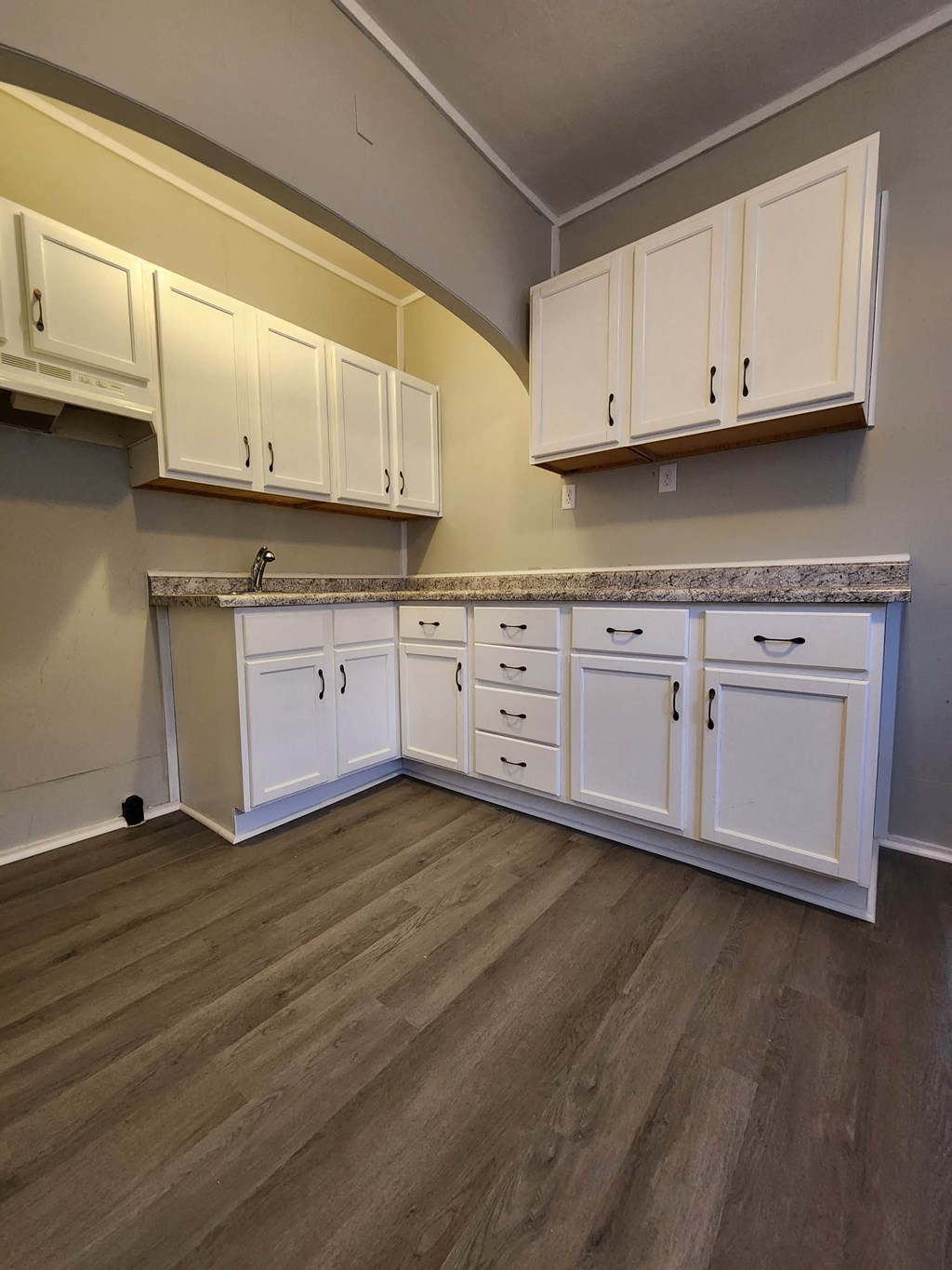 a kitchen with white cabinets and wooden floors