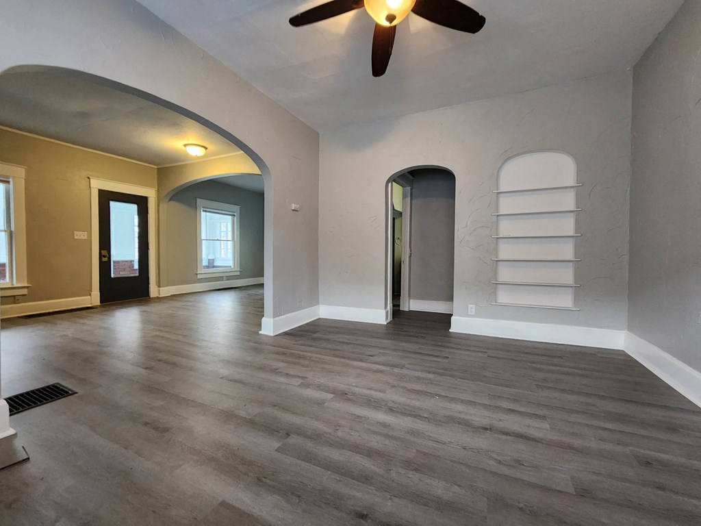 a empty living room with white walls and a ceiling fan