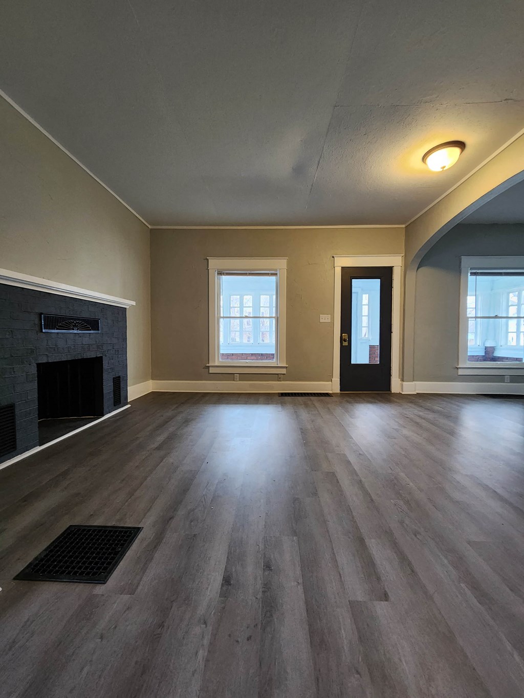 an empty living room with a fireplace and wooden floors