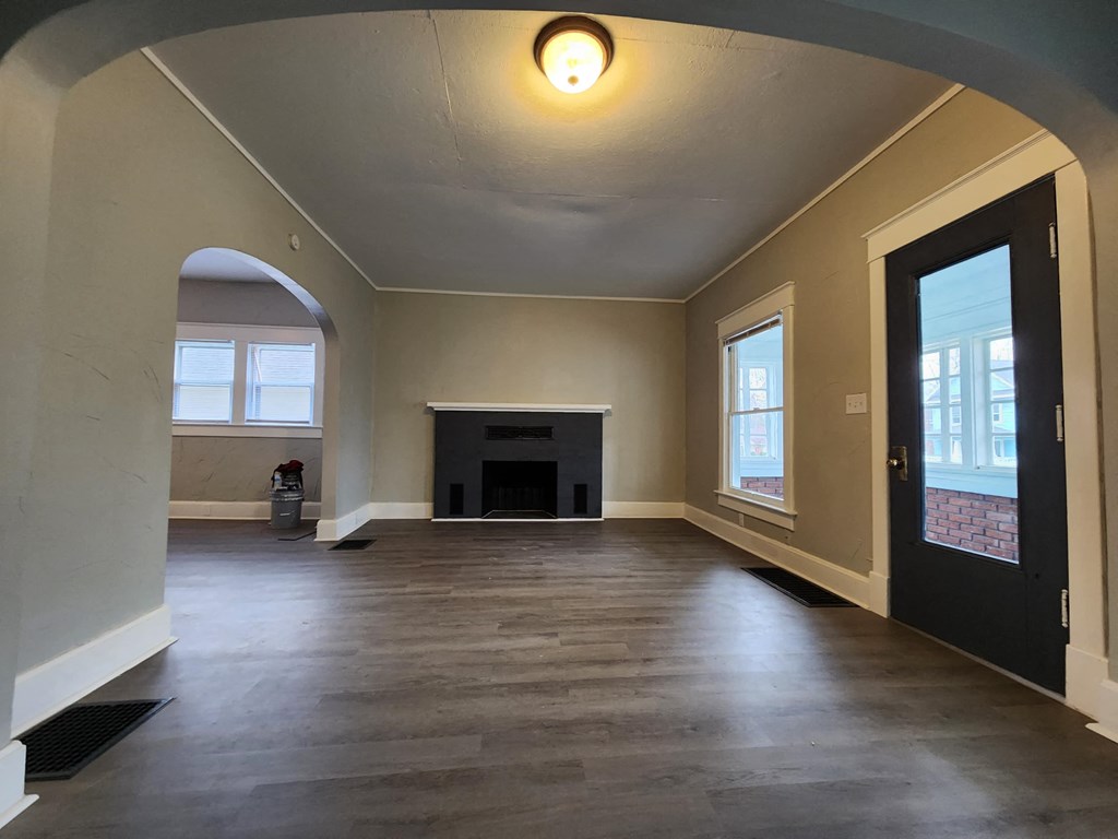 an empty living room with a fireplace and a door