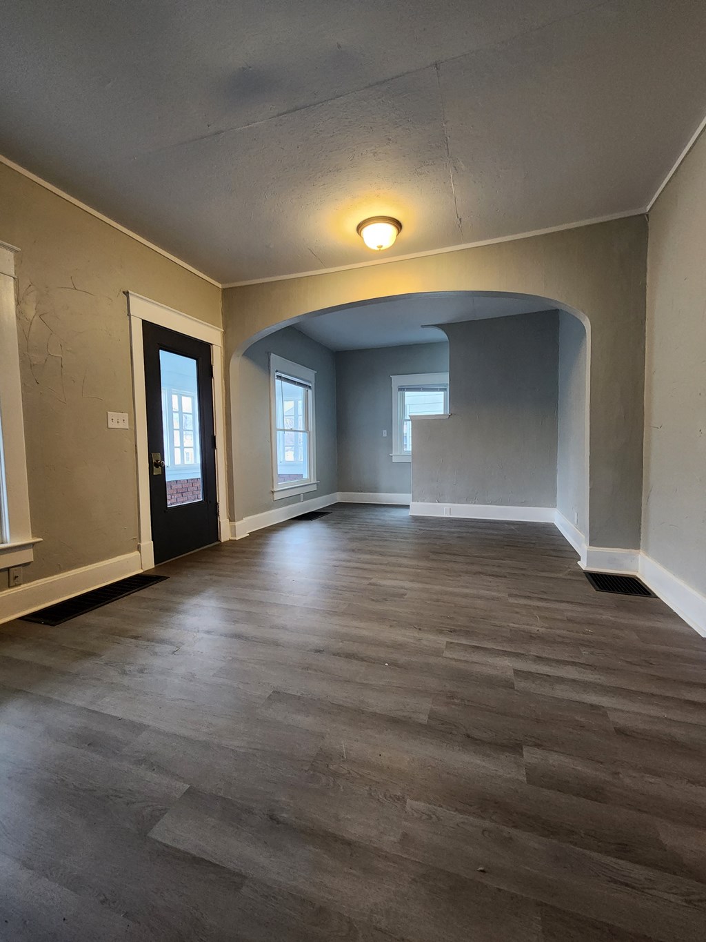 an empty living room with wood floors and a door