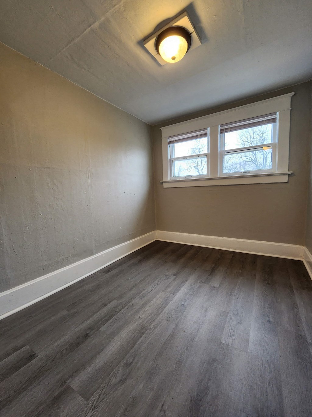 an empty room with wooden floors and a window