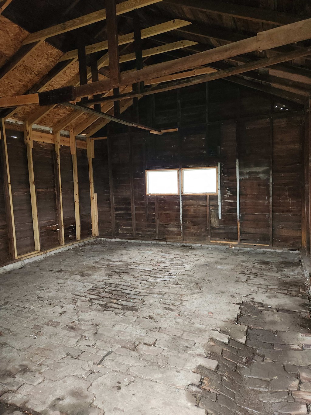 an empty attic with wooden walls and a stone floor