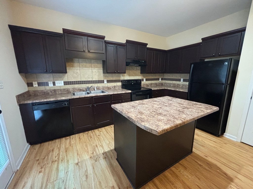A kitchen with dark brown cabinets and a granite countertop.