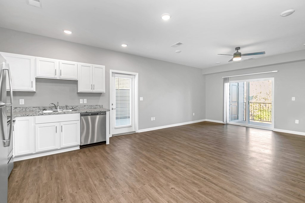 an empty kitchen and living room with a door to a balcony