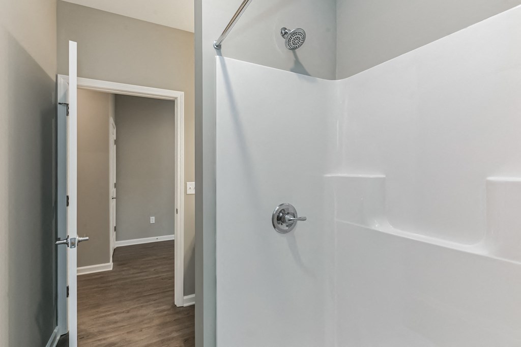 a white shower in a bathroom with a door to a closet