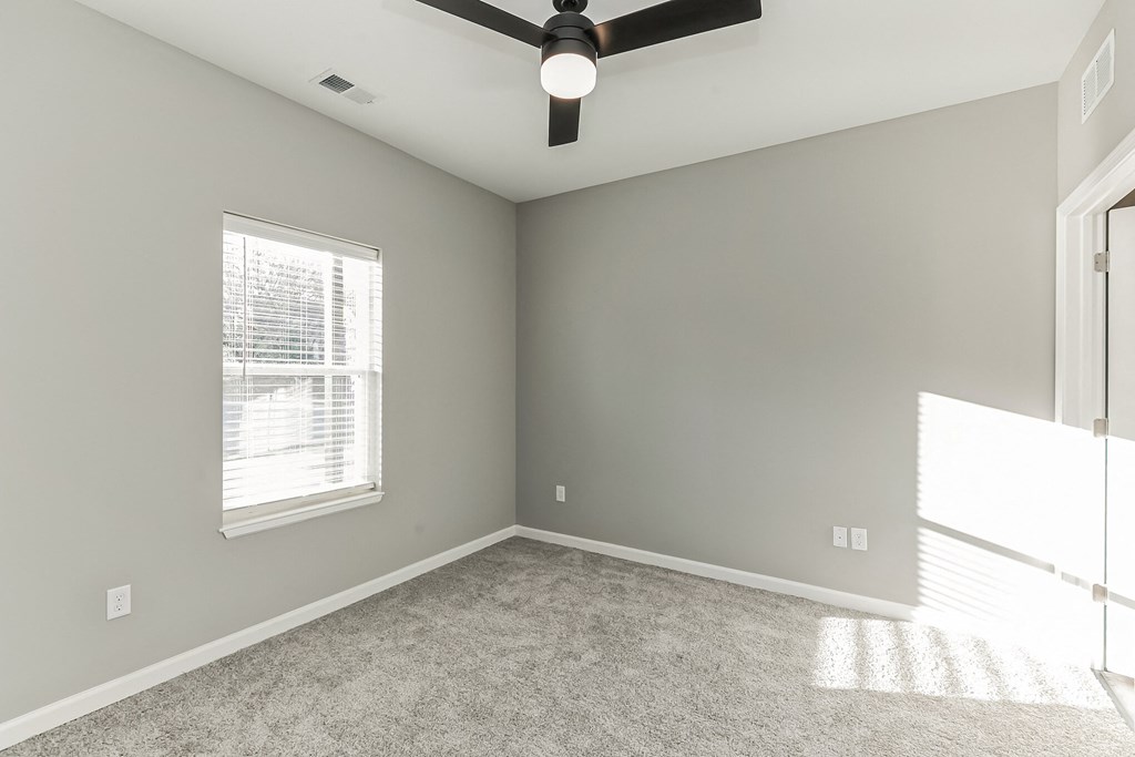 an empty room with a ceiling fan and a window