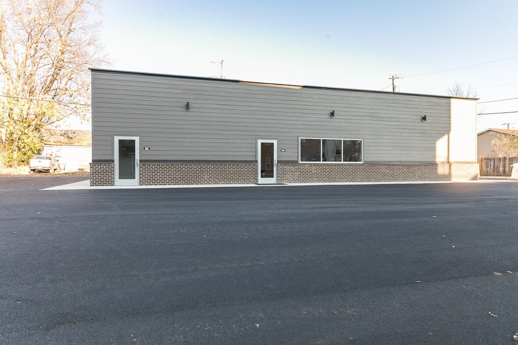 the front of a building with two doors and a parking lot