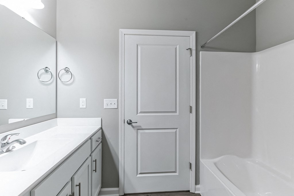 a bathroom with a white door and a sink and a shower