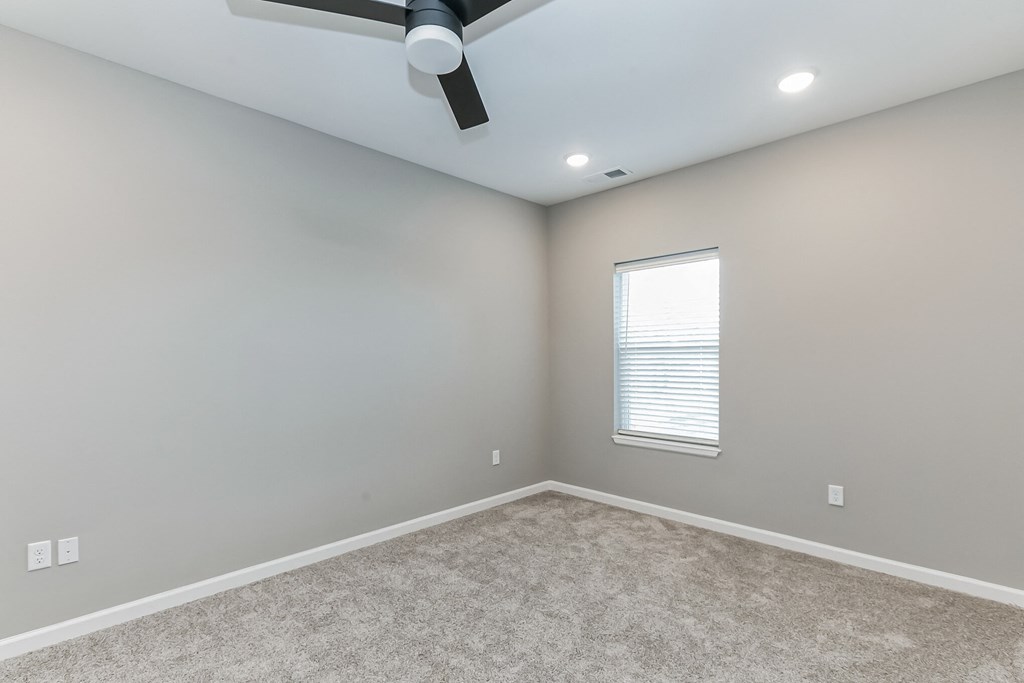 an empty room with a window and a ceiling fan