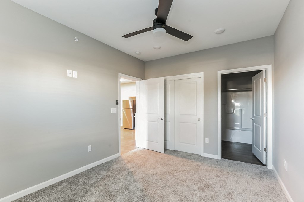 an empty living room with a ceiling fan and a door to a closet