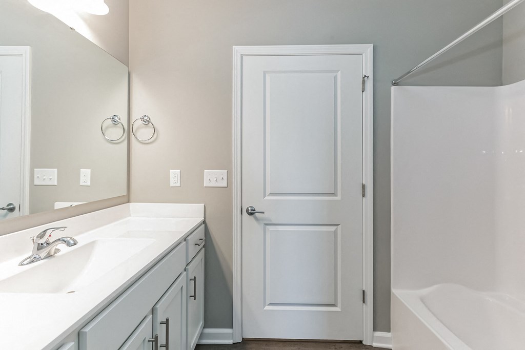 a bathroom with a white door and a sink and a mirror