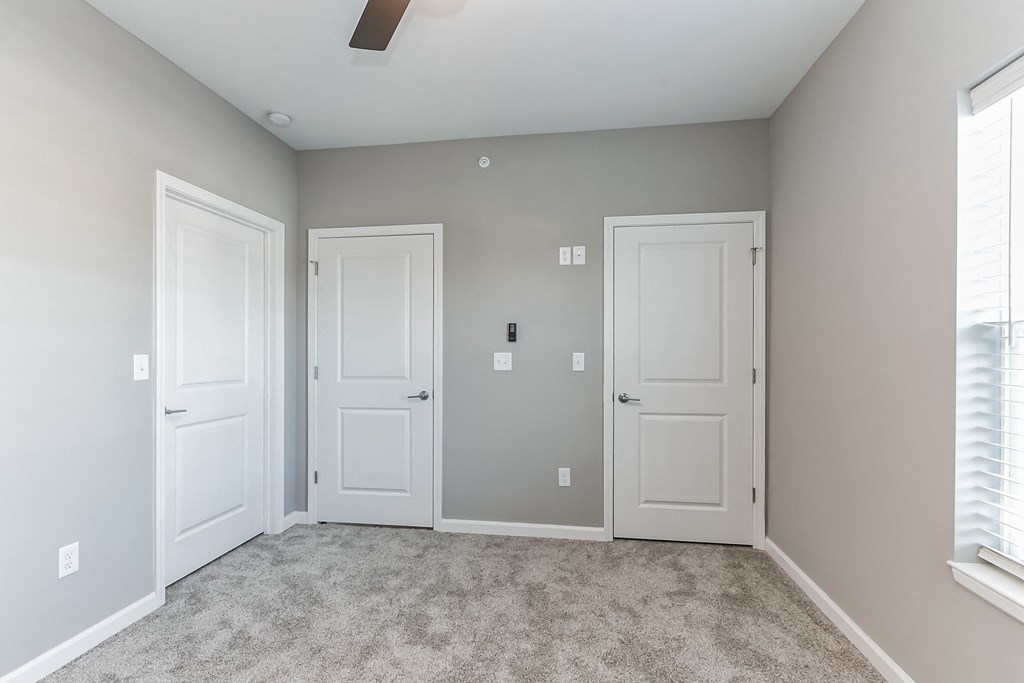 an empty room with two doors and a carpeted floor