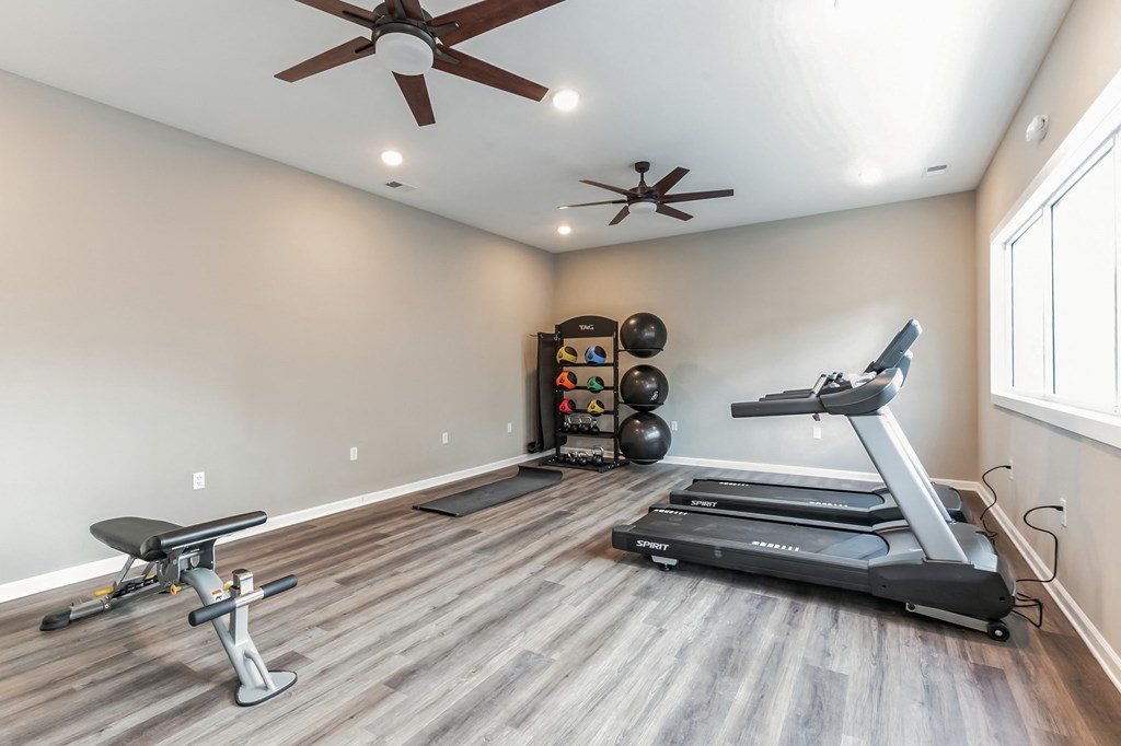 a home gym with a treadmill and a ceiling fan