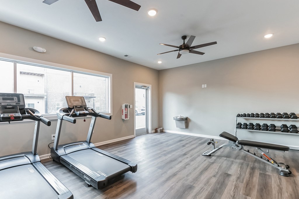 a gym with exercise equipment and a ceiling fan