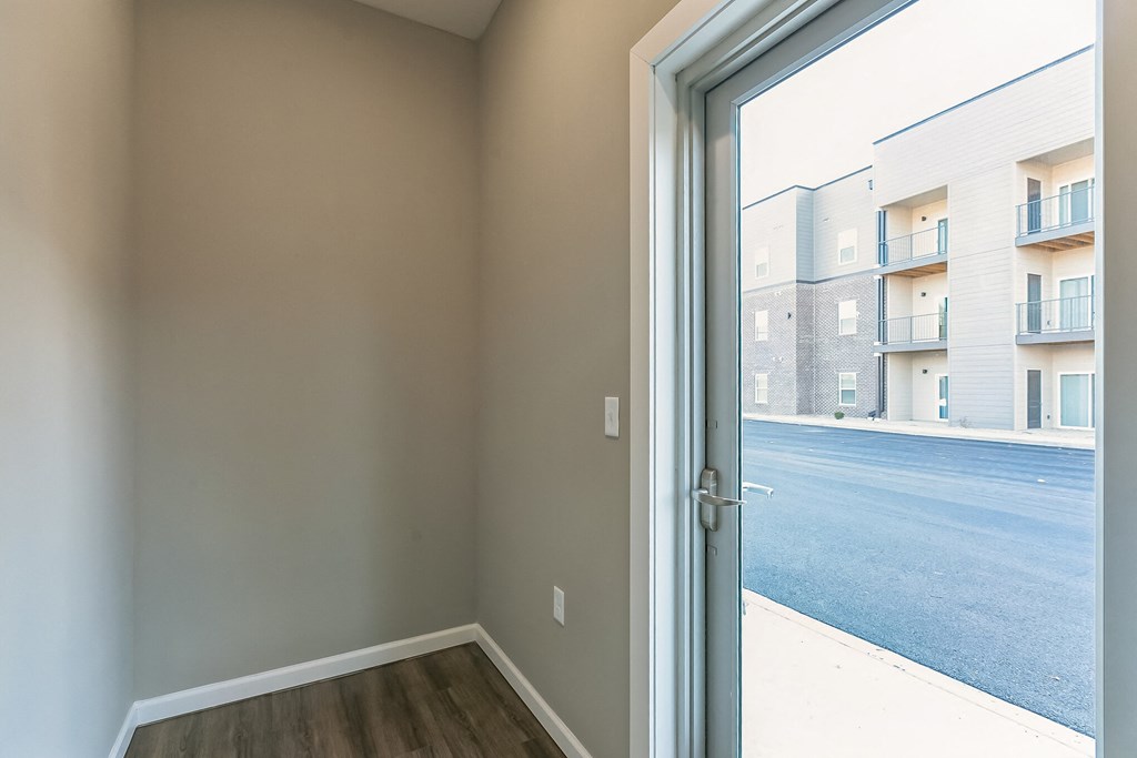 an empty room with a door to a street with apartment buildings