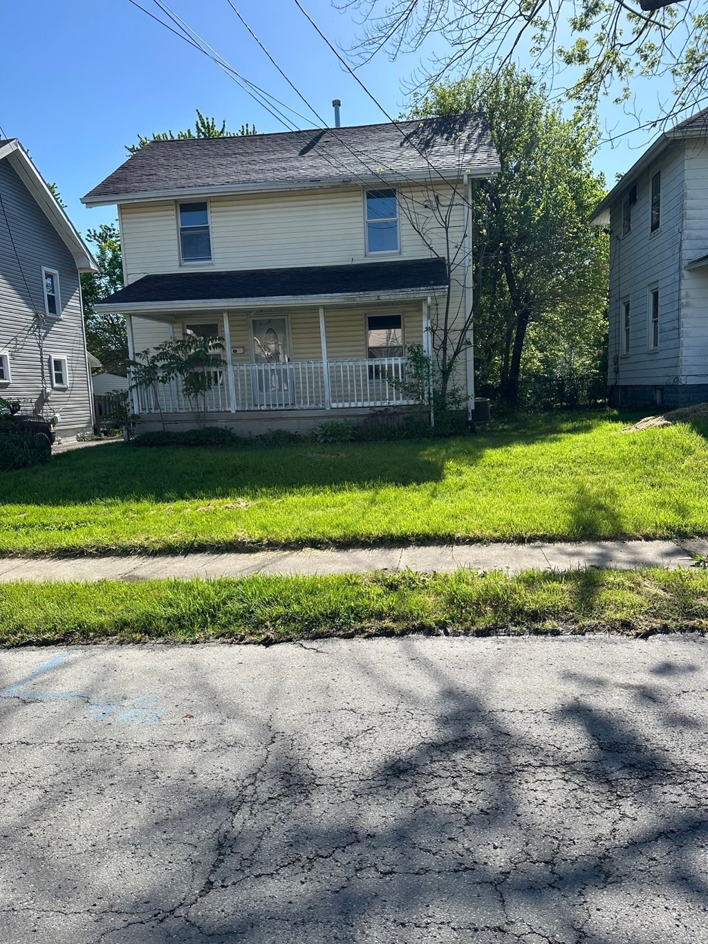 a white house with a porch and a sidewalk in front of it