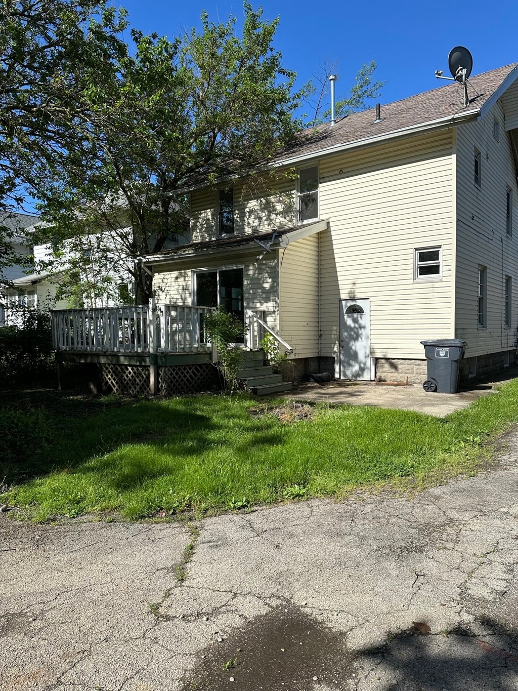 a white house with a porch and a tree in front of it