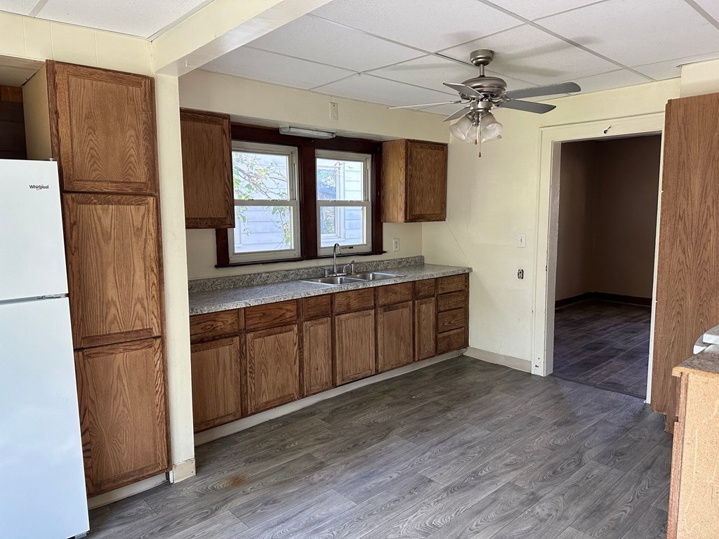 an empty kitchen with wooden cabinets and a ceiling fan