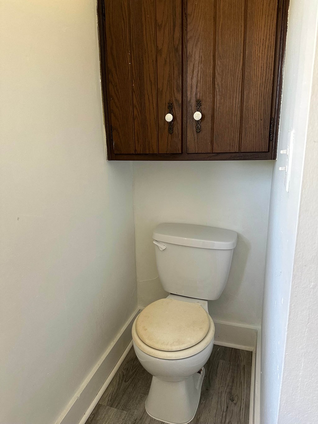 a bathroom with a toilet and a cabinet over it