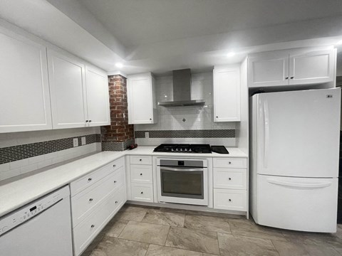 a kitchen with white cabinets and a white refrigerator