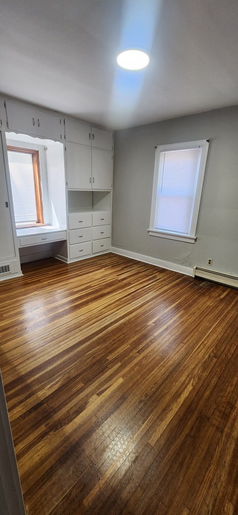 a living room with a hard wood floor and white cabinets