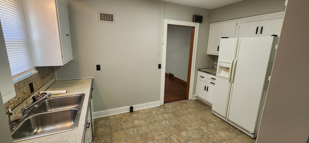 a kitchen with white cabinets and a sink and a refrigerator