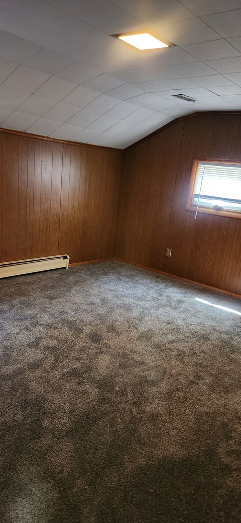 an empty room with wood paneling and a window