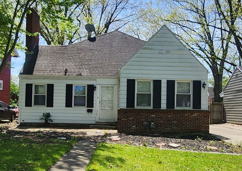 a white house with black shutters and a brick sidewalk