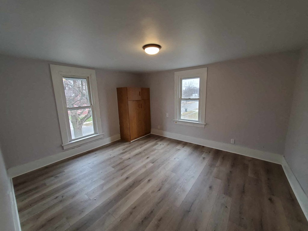 a living room with wooden floors and a door in the corner
