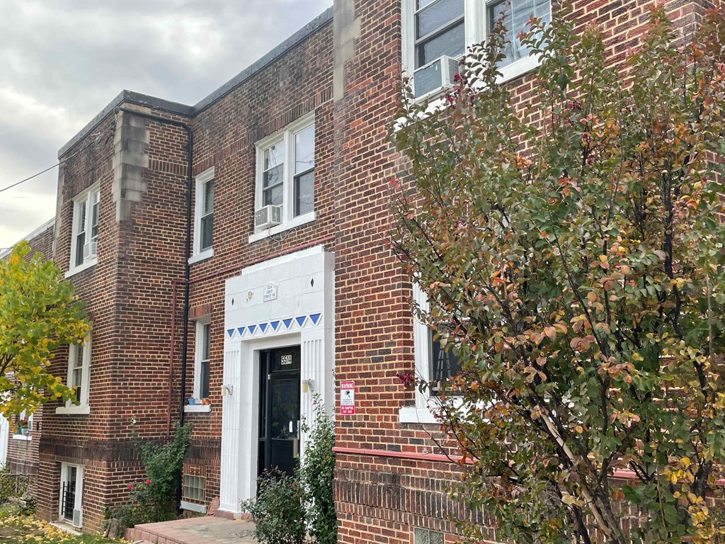 A brick building with a black door and a white trim around the windows.