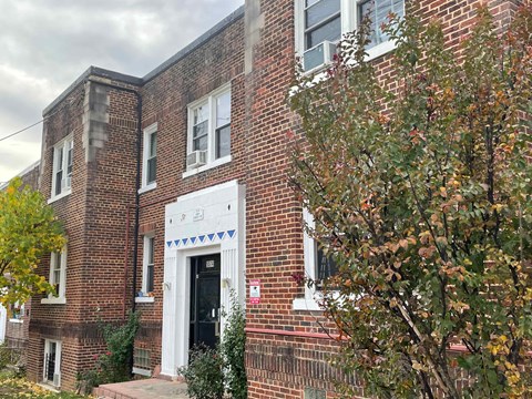 A brick building with a black door and a white trim around the windows.
